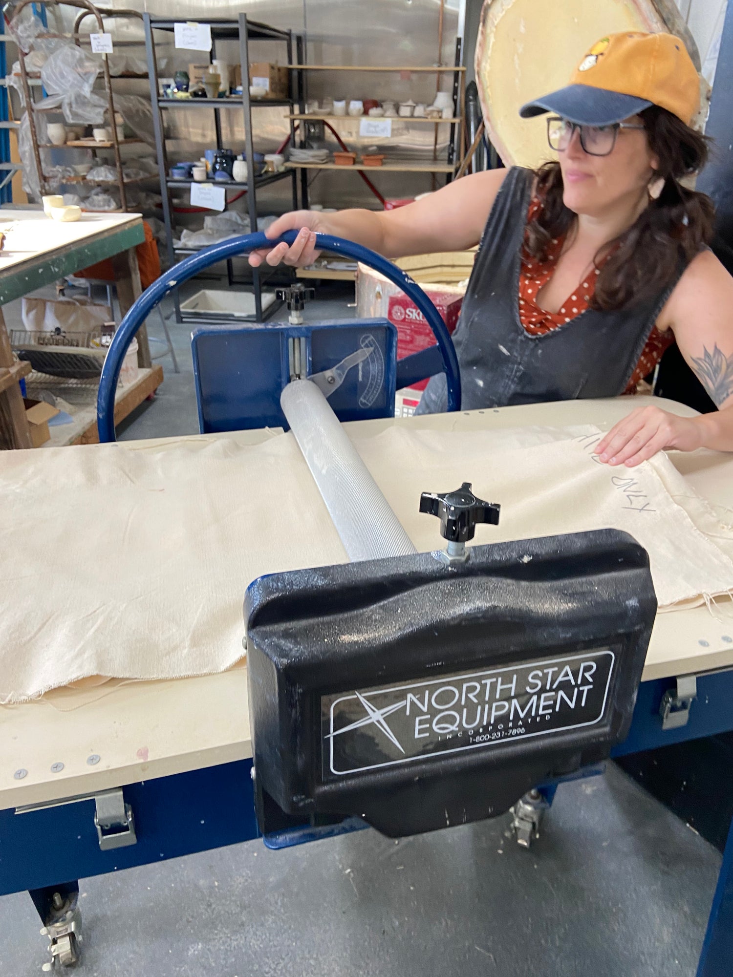 A potter flattening clay through a slab press